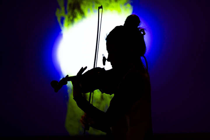 A silhouette of a woman playing the violin.